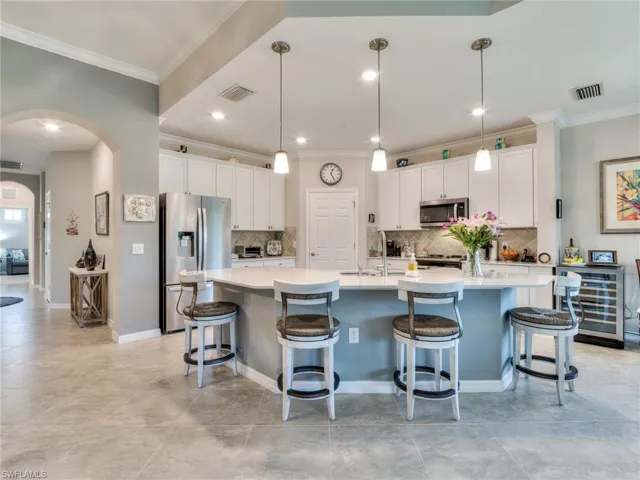 Kitchen with a kitchen breakfast bar, pendant lighting, backsplash, a kitchen island with sink, and appliances with stainless steel finishes
