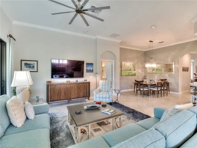 Living room featuring tile floors, ornamental molding, and ceiling fan with notable chandelier