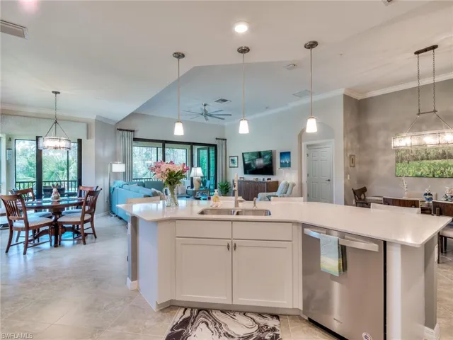Kitchen featuring sink, dishwasher, a center island with sink, and pendant lighting