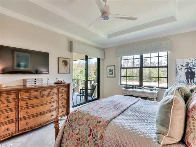Bedroom featuring ceiling fan, access to exterior, a raised ceiling, light tile floors, and ornamental molding