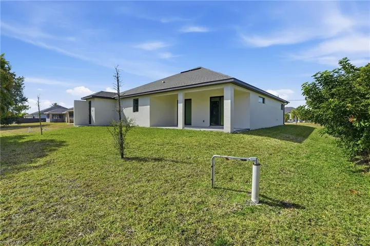 Back of property with a lawn, stucco siding, a patio area, and a shingled roof