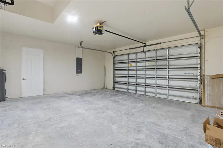 Garage with electric panel, a garage door opener, and electric water heater