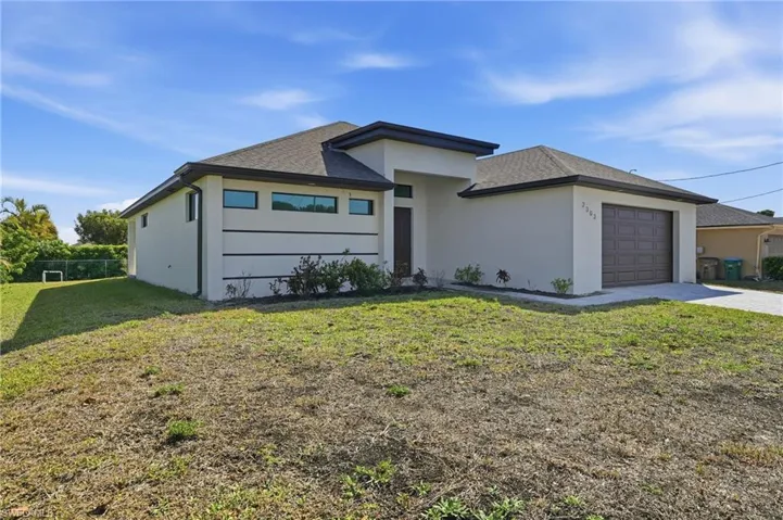 View of front facade with a front yard, stucco siding, a garage, and driveway