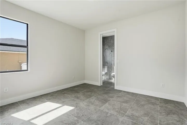 Unfurnished bedroom with baseboards and ensuite bath