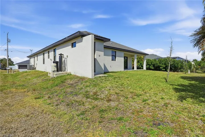 Back of property with stucco siding, a yard, and a patio