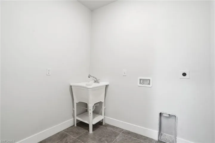 Laundry room featuring washer hookup, electric dryer hookup, and dark tile patterned floors
