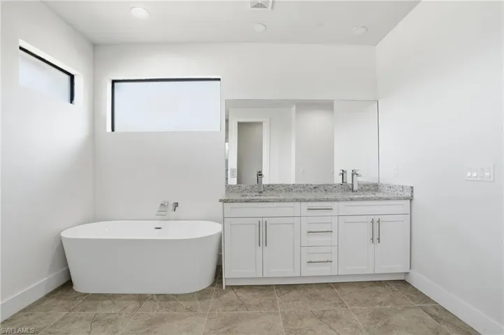 Full bath with a soaking tub, double vanity, and recessed lighting