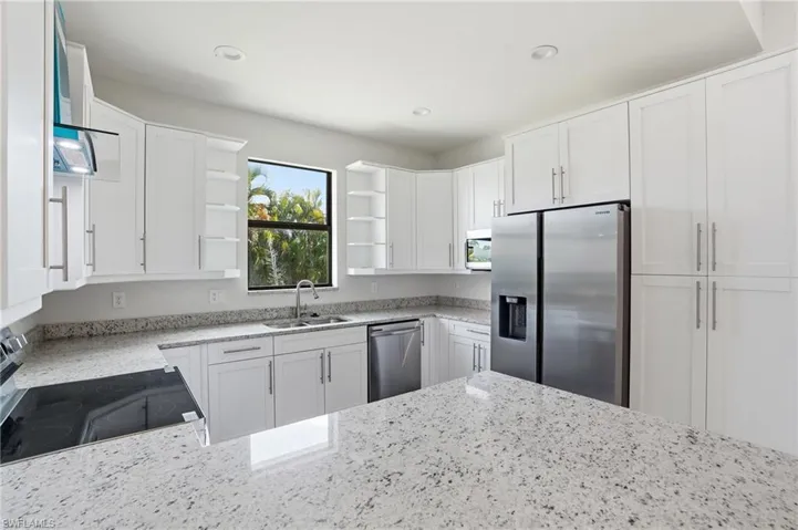 Kitchen featuring stainless steel appliances, light stone countertops, white cabinets, and recessed lighting