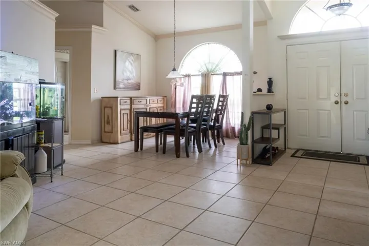 Tiled dining room featuring ornamental molding, a healthy amount of sunlight, and lofted ceiling