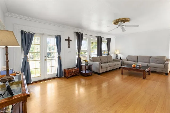 Living room with ornamental molding, light wood-style flooring, french doors, and ceiling fan