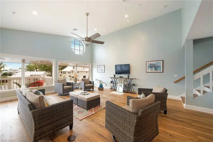 Living room featuring a towering ceiling, light wood-type flooring, and ceiling fan