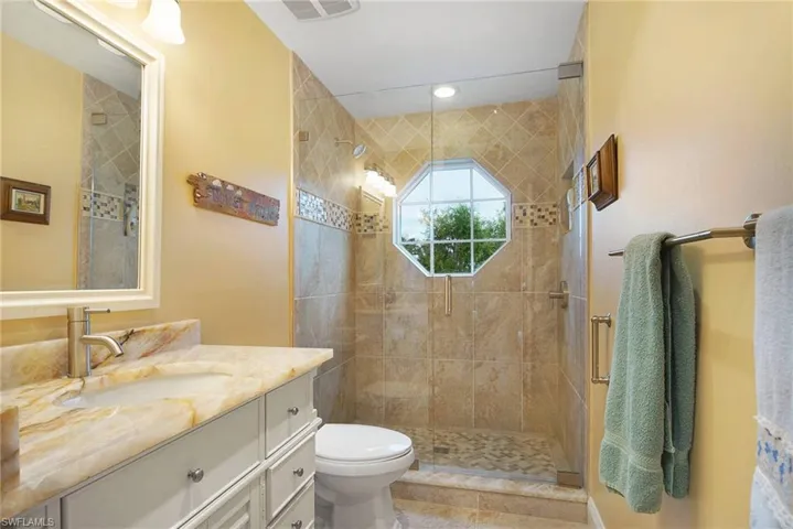 Bathroom with toilet, an enclosed shower, and vanity