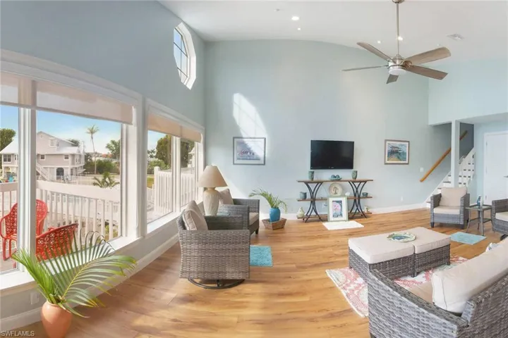 Living room with wood-type flooring, ceiling fan, and a wealth of natural light