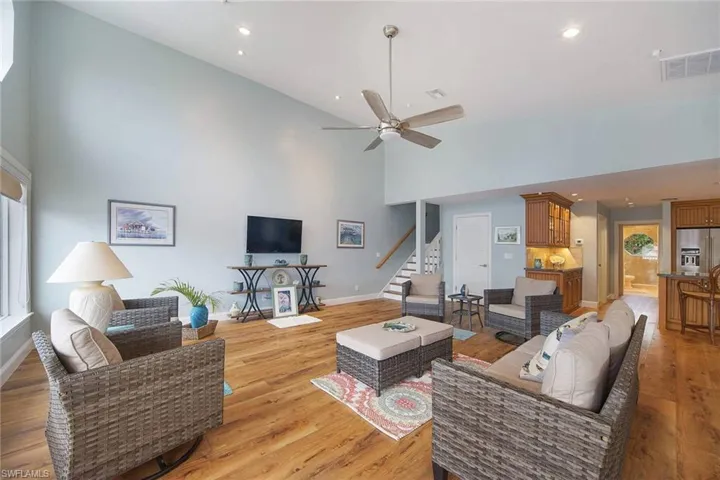 Living room with a high ceiling, ceiling fan, and light hardwood / wood-style floors