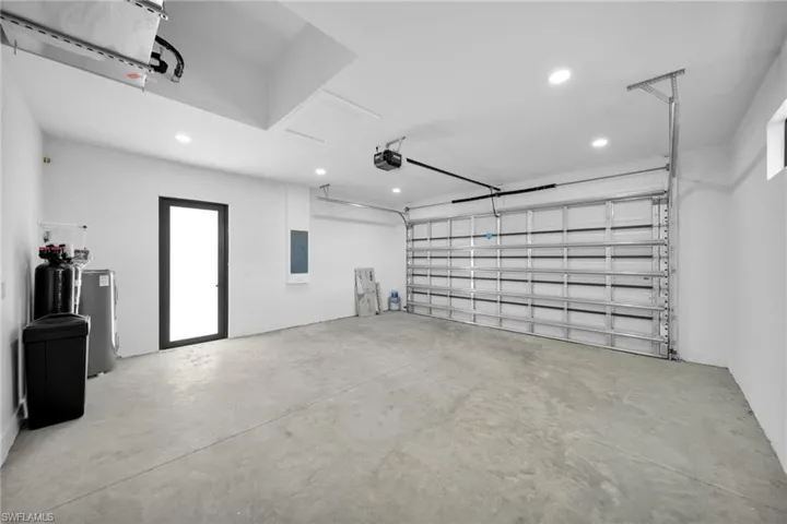 Garage featuring recessed lighting, electric panel, water heater, and a garage door opener