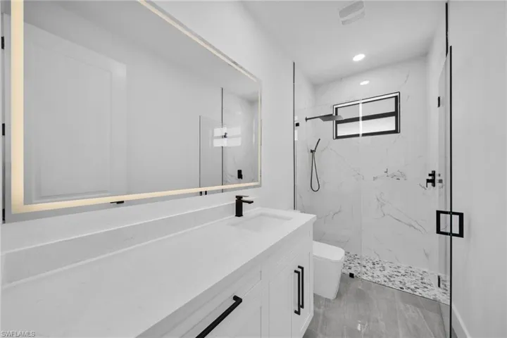 Full bathroom featuring a marble finish shower, vanity, and recessed lighting