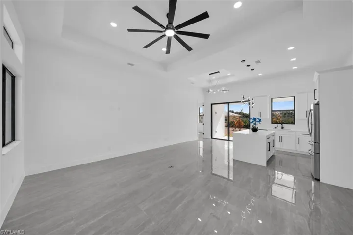 Unfurnished living room featuring a ceiling fan, a chandelier, and a tray ceiling