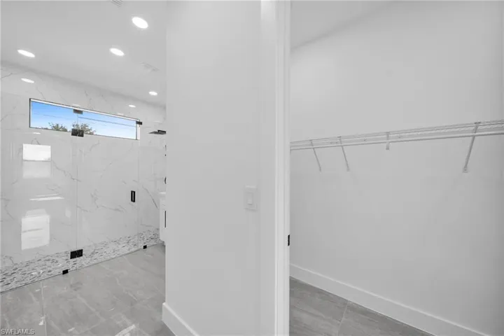 Bathroom featuring a walk in closet, a marble finish shower, and recessed lighting