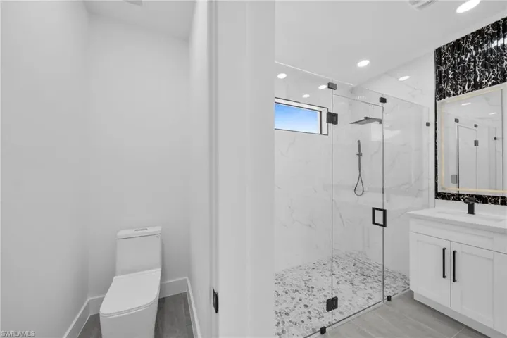 Full bath featuring vanity, a marble finish shower, recessed lighting, and light wood-style floors