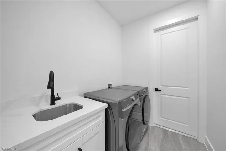 Laundry area with independent washer and dryer, light wood-style floors, and cabinet space