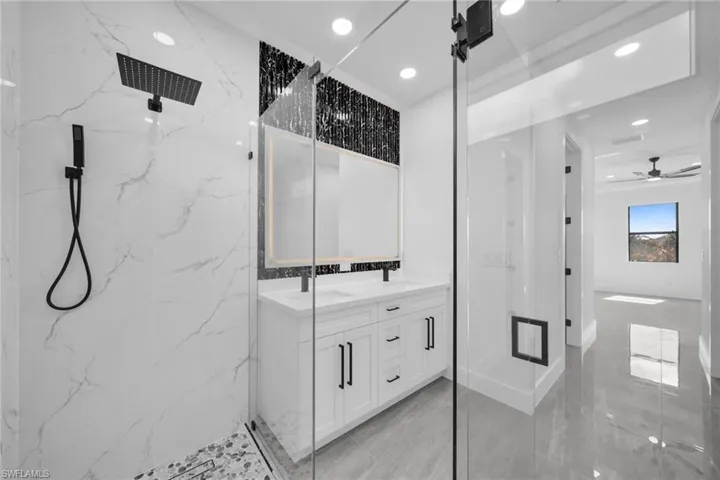 Full bath featuring a marble finish shower, double vanity, recessed lighting, and a ceiling fan