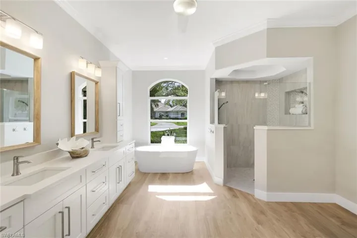 Bathroom featuring vanity, plus walk in shower, ornamental molding, and hardwood / wood-style flooring