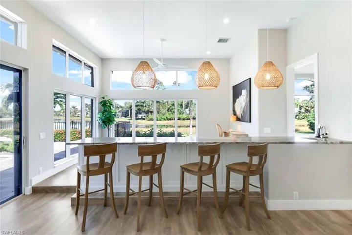 Kitchen featuring light stone countertops, wood-type flooring, hanging light fixtures, and a high ceiling