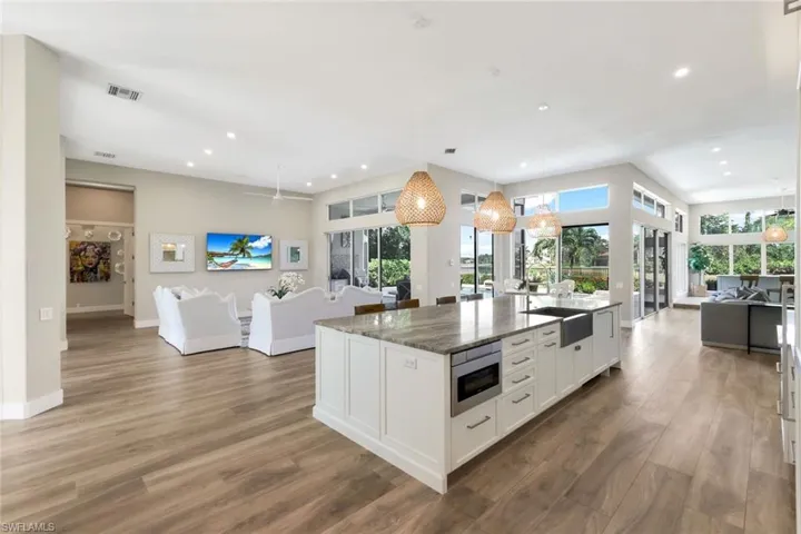 Kitchen featuring stainless steel microwave, dark stone countertops, decorative light fixtures, white cabinets, and hardwood / wood-style flooring