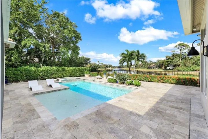 View of swimming pool with a water view, a patio, and a hot tub