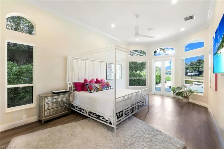 Bedroom with hardwood / wood-style floors, access to outside, multiple windows, and ceiling fan