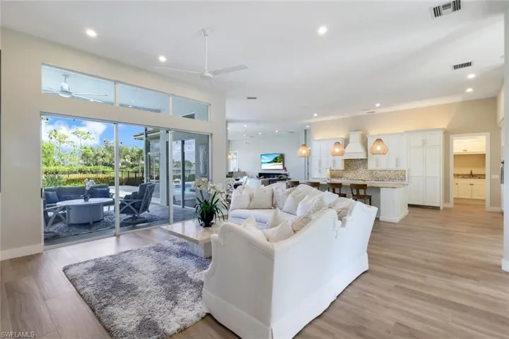Living room with a high ceiling, light hardwood / wood-style floors, and ceiling fan