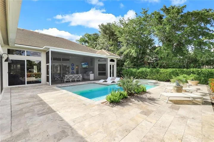 View of swimming pool with a sunroom, a patio area, and a jacuzzi