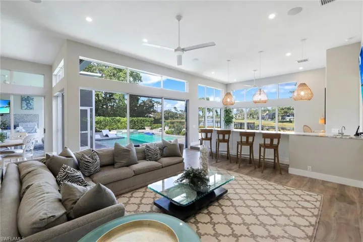 Living room with hardwood / wood-style floors, ceiling fan, a healthy amount of sunlight, and a towering ceiling