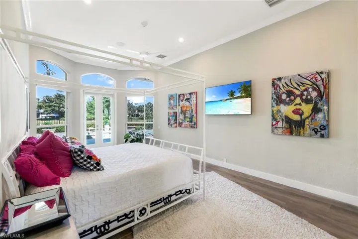 Bedroom with dark hardwood / wood-style floors, crown molding, and french doors