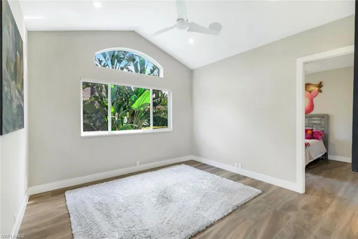 Empty room with ceiling fan, lofted ceiling, and hardwood / wood-style flooring