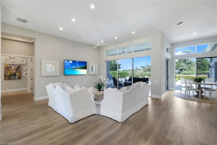 Living room featuring hardwood / wood-style floors, ceiling fan, a high ceiling, and a wealth of natural light