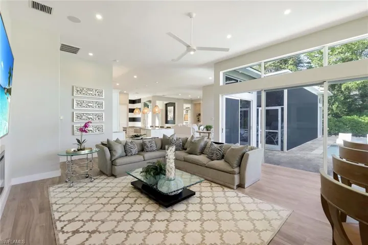 Living room with ceiling fan, a high ceiling, and light hardwood / wood-style flooring