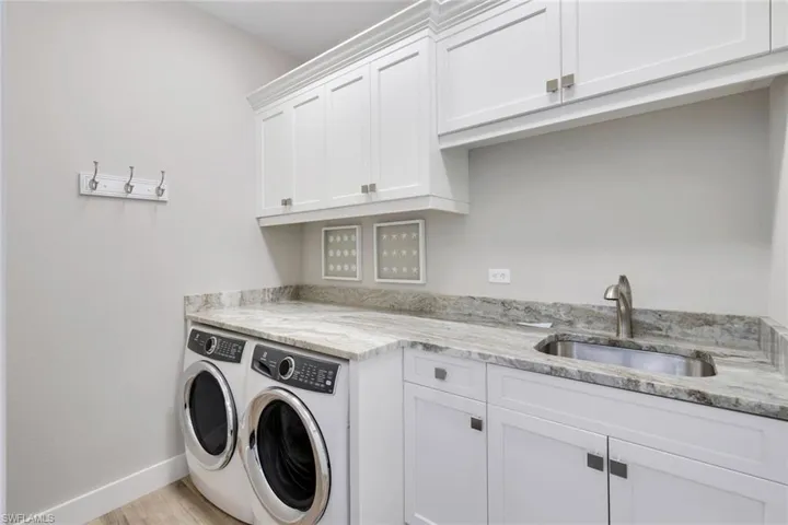 Laundry area with cabinets, separate washer and dryer, light hardwood / wood-style floors, and sink