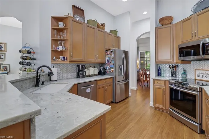 Kitchen with backsplash, light hardwood / wood-style flooring, stainless steel appliances, and sink