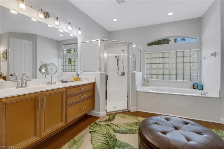 Bathroom with shower with separate bathtub, wood-type flooring, and vanity