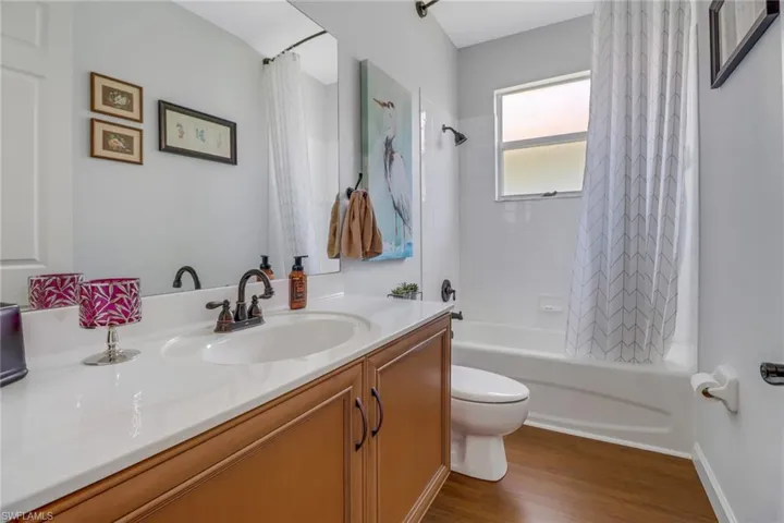 Full bathroom with shower / bathtub combination with curtain, toilet, vanity, and wood-type flooring