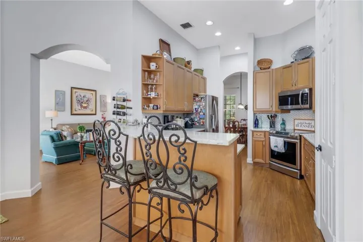 Kitchen featuring stainless steel appliances, a breakfast bar area, backsplash, light hardwood / wood-style flooring, and kitchen peninsula