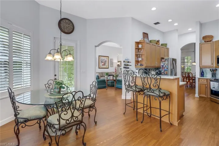 Kitchen with a breakfast bar area, a notable chandelier, stainless steel appliances, backsplash, and light hardwood / wood-style flooring