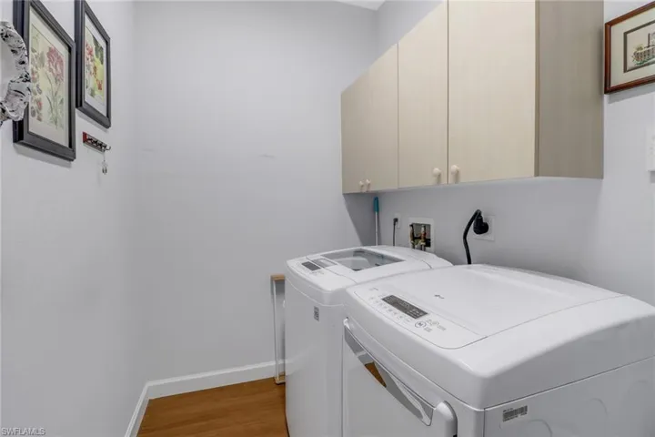 Laundry area featuring cabinets, dark wood-type flooring, and washer and clothes dryer