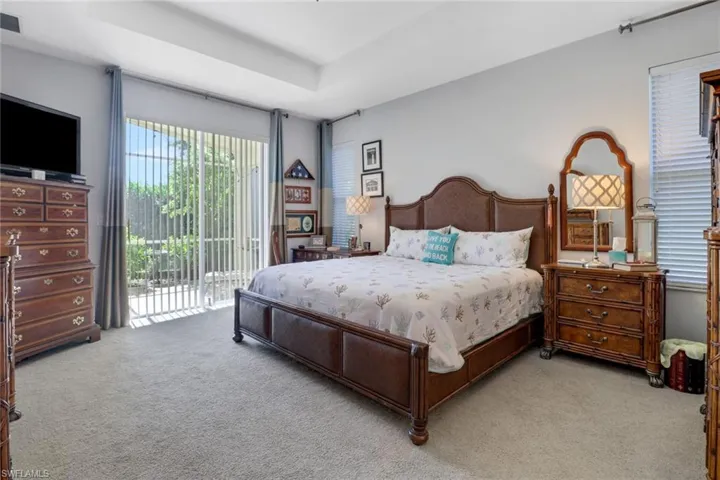 Carpeted bedroom with a raised ceiling and access to outside