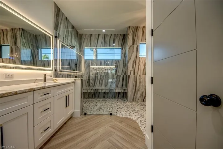 Bathroom with tiled shower, vanity, and tile walls