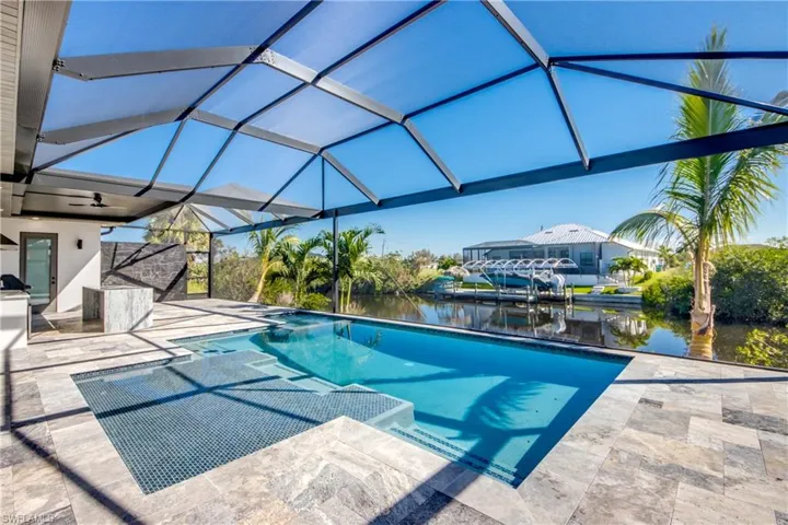 View of swimming pool with a water view, glass enclosure, and a patio area