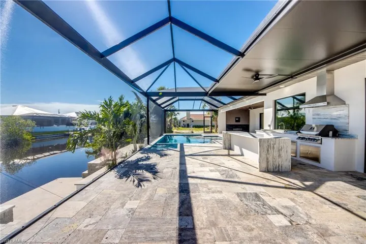 View of swimming pool featuring ceiling fan, an outdoor kitchen, a patio area, area for grilling, and a lanai