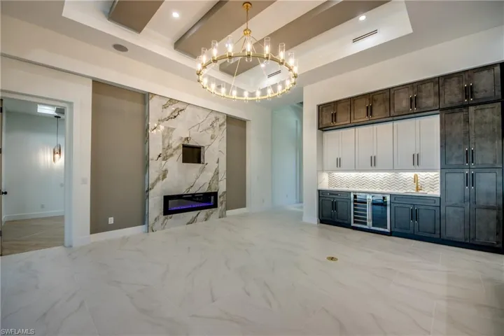 Bar featuring pendant lighting, dark brown cabinets, decorative backsplash, and a raised ceiling