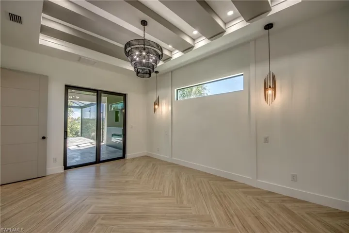 Spare room featuring a notable chandelier, beam ceiling, and light parquet flooring